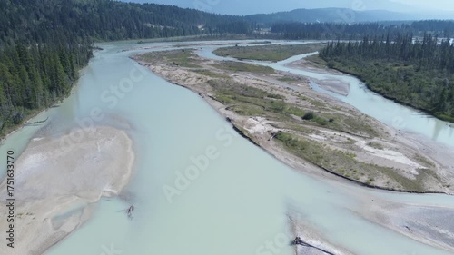 Cinematic aerial footage follows the course of a massive, untamed river in a remote valley. The camera reveals the network of channels and islands created by the powerful water flow.