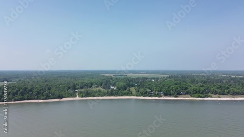 This beautiful aerial footage shows the endless shoreline of a large lake or river. The calm water and green forest create a peaceful, scenic background perfect for nature documentaries or travel cont