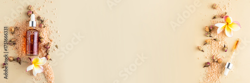 Holistic skin care still life and spa essentials banner serum bottle bath salts, and a frangipani bloom.