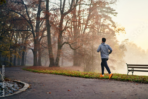 Man running in a foggy autumn morning in park