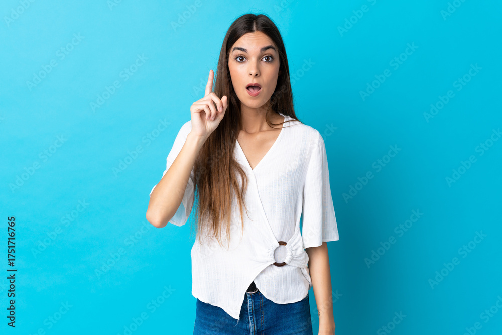 Fototapeta premium Young caucasian woman isolated on blue background intending to realizes the solution while lifting a finger up