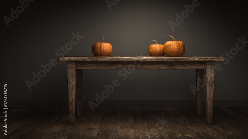 Simple autumn decoration with three small pumpkins arranged on rustic wooden table in minimalistic setting with dark background