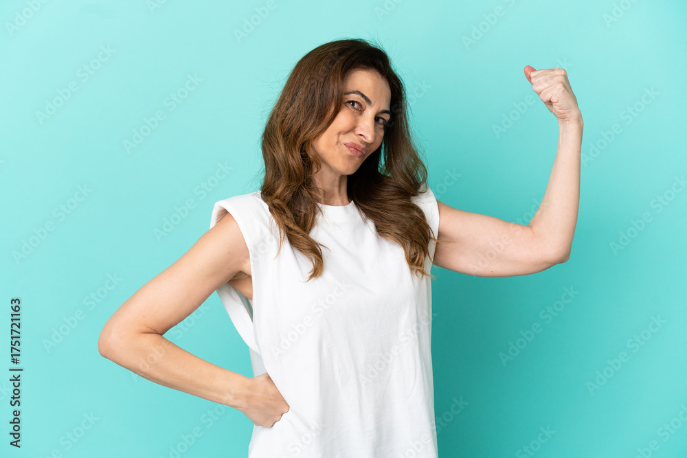 Fototapeta premium Middle aged caucasian woman isolated on blue background doing strong gesture