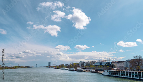 Modern European City Riverfront with Boats under Blue Sky