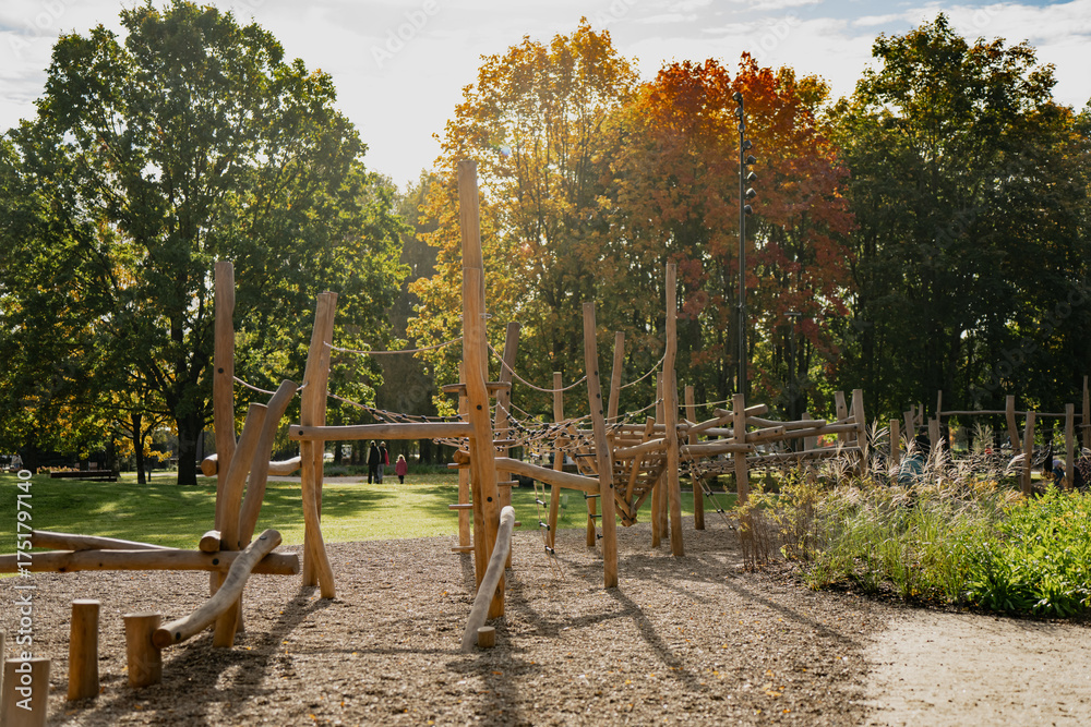 Fototapeta premium Modern wooden playground climbing structure with rope elements in public park surrounded by trees designed for outdoor recreation physical activity and safe child development