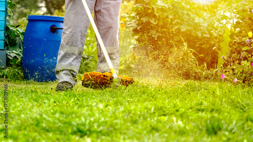 Bild auf Leinwand Gardener with trimmer mowing lawn