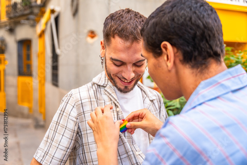 Fényképezés Gay man attaching pride pin to partner's shirt