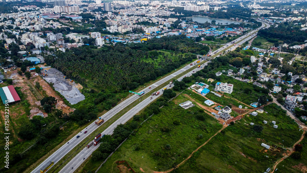 Fototapeta premium Arial shot of Beautiful road infrastructure of karnataka in India. Aerial view city traffic Highway road with car vehicle movement in Bangalore.