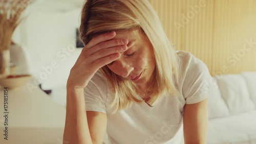 Woman Holding Head Feeling Unwell in Bright Living Room
