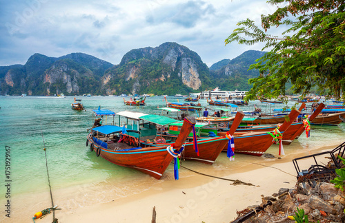 Thailand. Longtail boats on the beach at Phuket. Famous Koh Phi-Phi Don island with white sand beach and turquoise water under blue sky. Vacation holidays summer background in Phuket, Thailand.