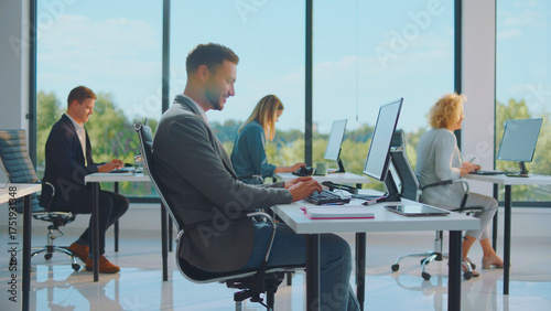 Billede på lærred Diverse office workers staying productive at their desks, using computers in a b
