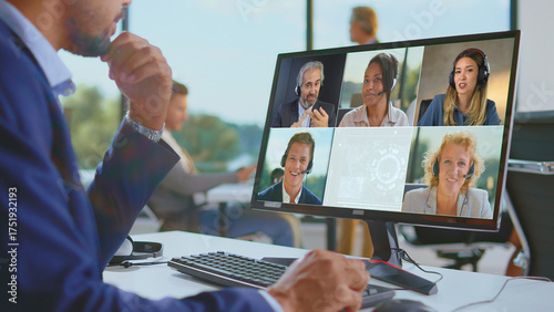 Business professional engaging in a virtual video meeting with diverse colleagues on a desktop computer, collaborating and communicating remotely from an office environment