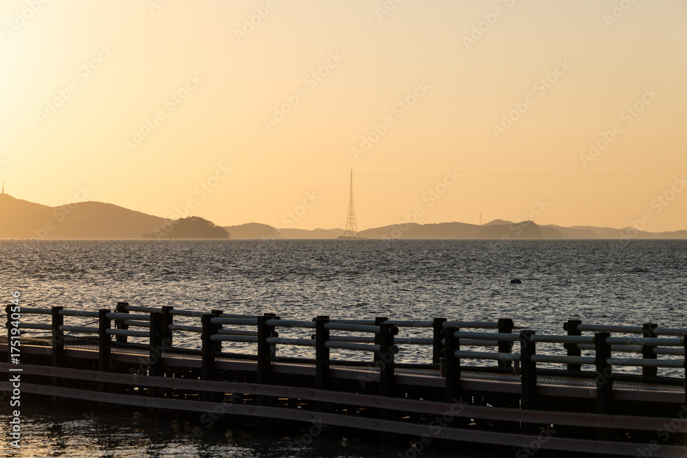 Obraz premium idyllic seascape with island, pylon and pier during sunset