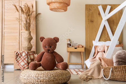 Toy bear on pouf in childre...