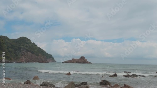 A peaceful coastal time-lapse video showing waves and clouds moving under a bright blue sky
