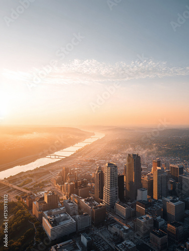 Sunrise over a cityscape, bathed in golden light. A river winds through the urban landscape. Ideal for business, travel, or inspirational themes. Growth and ambition.