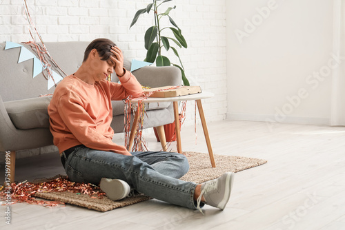 Young man with hangover sit...