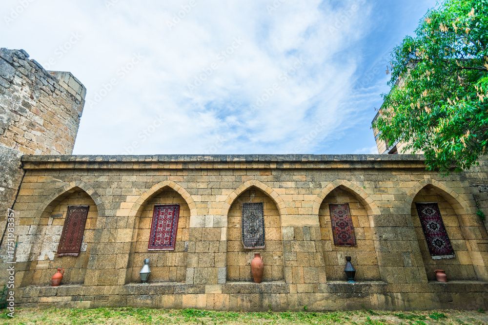 Naklejka premium The inner side of the old fortress wall of the Naryn Kala citadel decorated with carpets and jugs. Dagestan