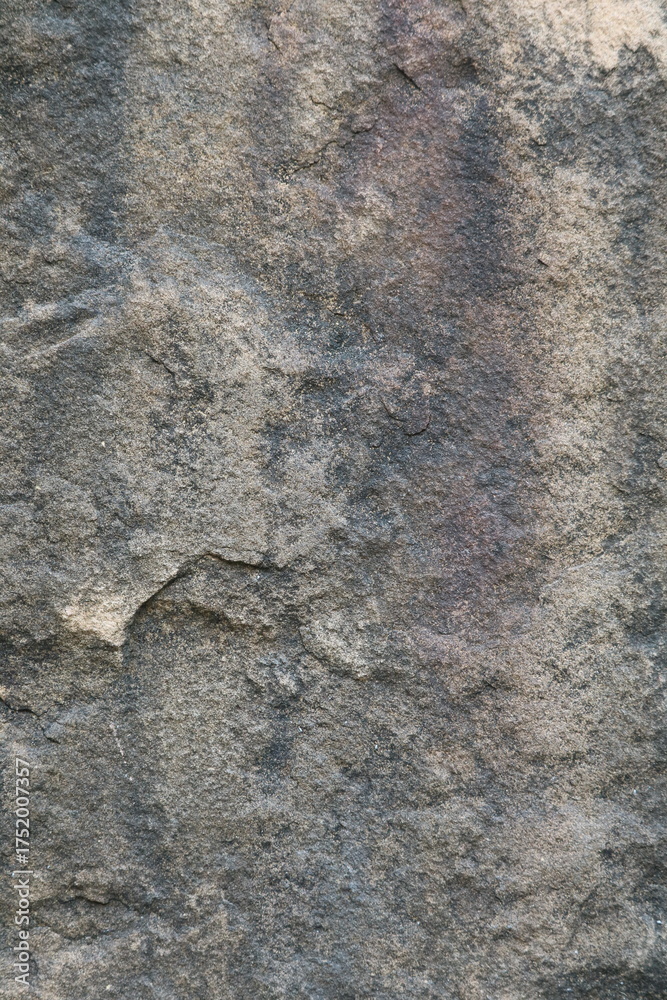 Naklejka premium Close-up view of rough textured stone surface with natural patterns and colors, ideal for backgrounds, wallpapers, and design projects.