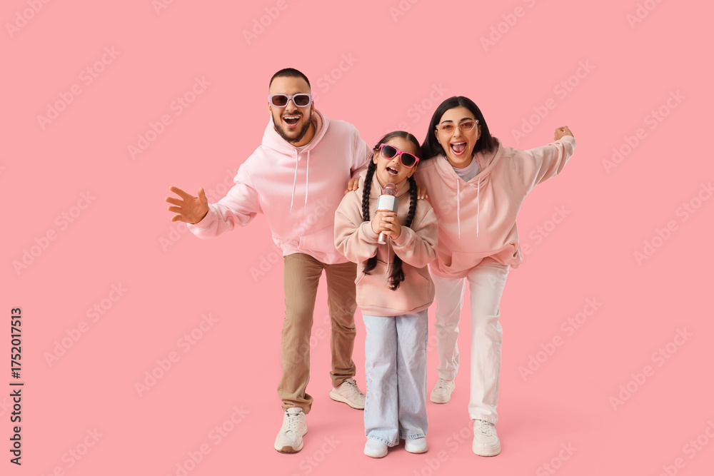 Fototapeta premium Happy family in sunglasses with microphone singing on pink background