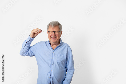 Wallpaper Mural sixty years old man with blue shirt inserting his hearing aid Torontodigital.ca