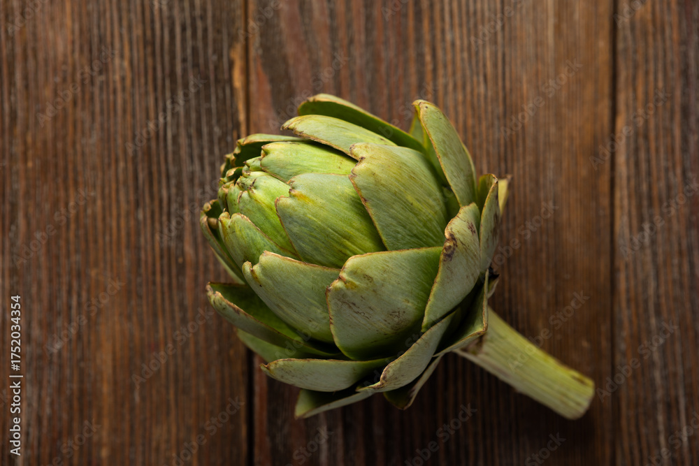 Fototapeta premium Overhead view of artichoke flower in wooden board