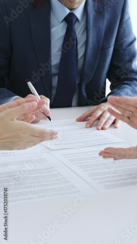 Businessman signing a contract papers at the white desk in office, colleagues applauding to the successful results of negotiations. Business people concept