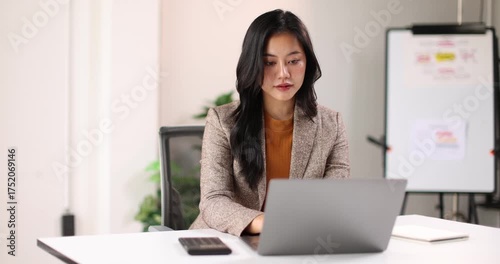Adult woman working at her desk in a bright office, business casual jacket digital nomad remote work concept
