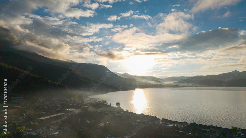 Fototapeta premium Villages by the Sunrise Lake and distant mountains, Lugu Lake in Sichuan, China
