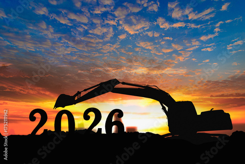 Concept happy new year 2026,crawler excavator silhouette with lift up bucket .On sunset backgrounds