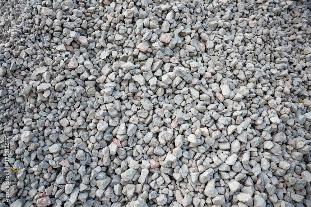 Obraz premium A detailed view of a pile of small gray stones with irregular shapes, featuring scattered hints of pink and beige tones across the rugged surface.