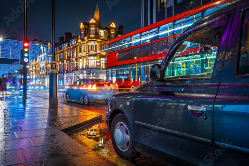 Photography Classic red double-decker bus on festive London street at night