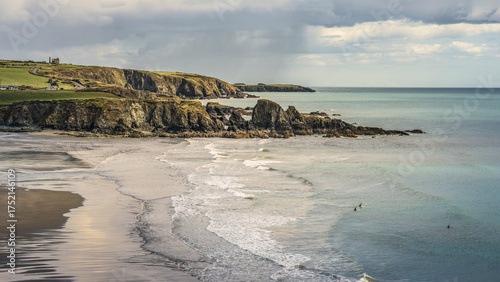 Foto Scenic high-angle view of Irish coast, cliffs, sea stacks, and surfers beneath overcast Atlantic sky