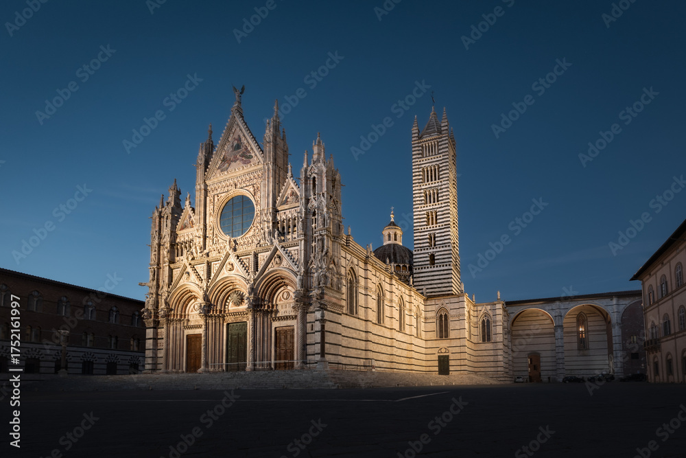 Fototapeta premium Night cityscape with illuminated facade of Duomo di Siena gothic cathedral and empty square, Italy