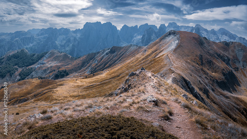 Sunlit hillside narrow hiking path distant rocky peaks on sunny day, Prokletije, Montenegro