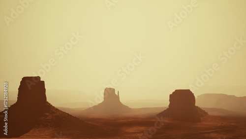 During a tranquil sunset, the sun casts an amber glow over the iconic rock formations of Monument Valley. The desert landscape is bathed in warm hues, showcasing natures beauty.