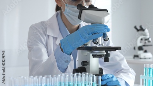 Принти на полотні Scientist wearing protective gear carefully adjusting microscope lens, analyzing