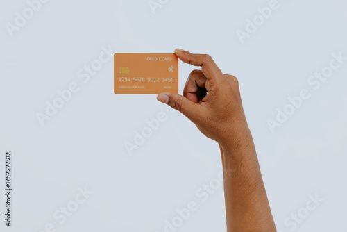 Hand holding orange a credit card isolated over white background.