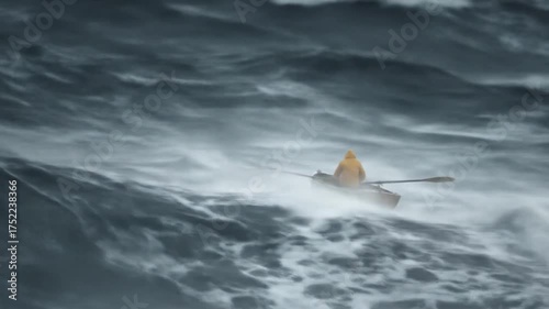 Small boat navigates rough waters under stormy sky with oarsman