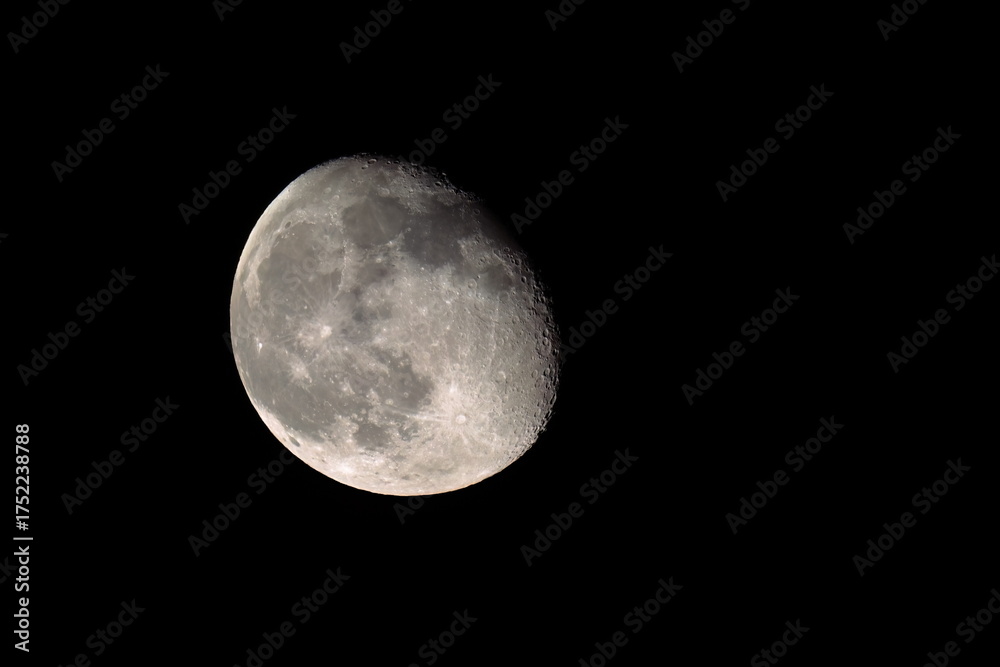 Obraz premium Nearly full moon displaying craters in the black night sky. 