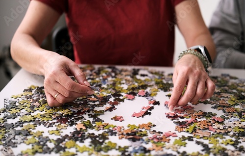 Woman's Hands Putting A Puzzle Together On The Table, A Hobby For The Whole Family