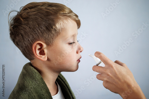 Parent helping child use nasal aspirator for stuffy nose