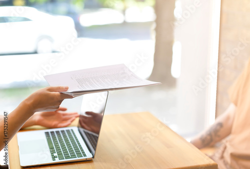 Bild auf Leinwand Interview, in the hands of a woman papers, a young man sits at a wooden table