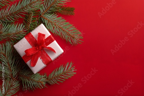 Festive Gift Box Decorated With Ribbon and Pine Branches on Red Background fo...