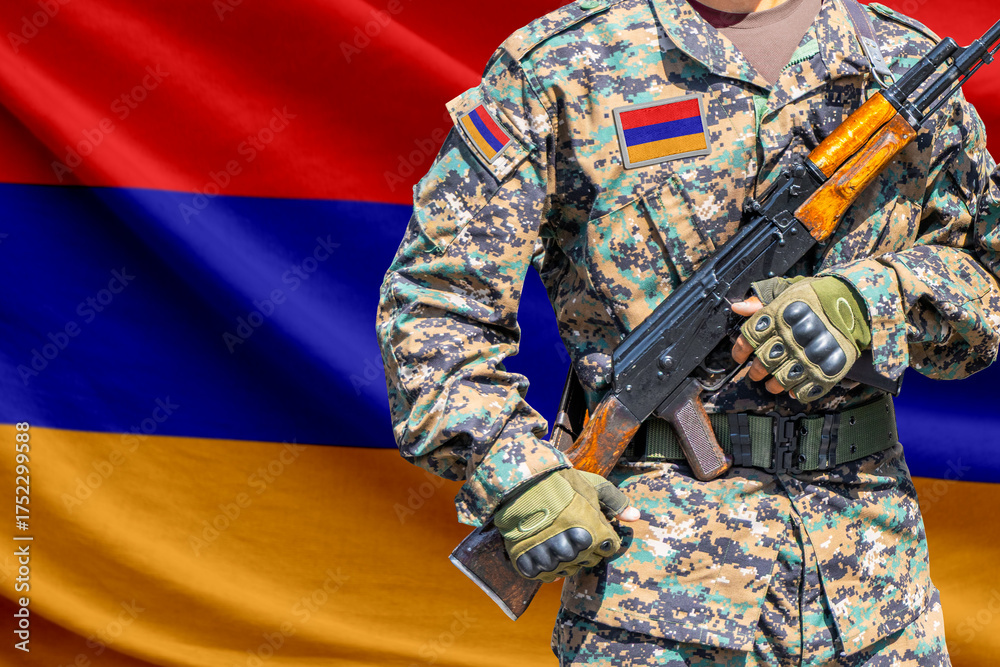 Fototapeta premium Armenia flag with soldier in military uniform holding assault rifle in front of it