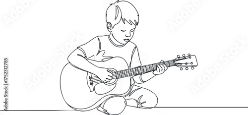 A young boy sitting and playing an acoustic guitar, engaging in music and creativity.