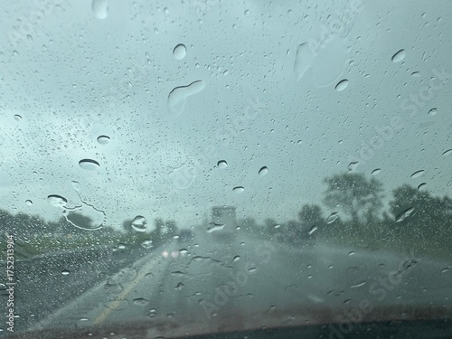 Rainfall creates a blurred view on a highway during a cloudy day in the countryside