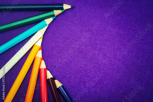Nine multicolored pencils on a purple felt background. Different colored pencils with space for text. Back to school. Art lessons.
