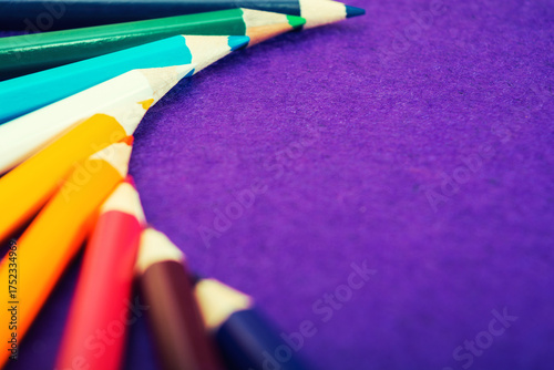 Nine multicolored pencils on a purple felt background. Different colored pencils with space for text. Back to school. Art lessons.