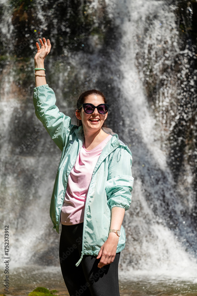 Fototapeta premium Young Happy Woman standing in front of spring waterfall 